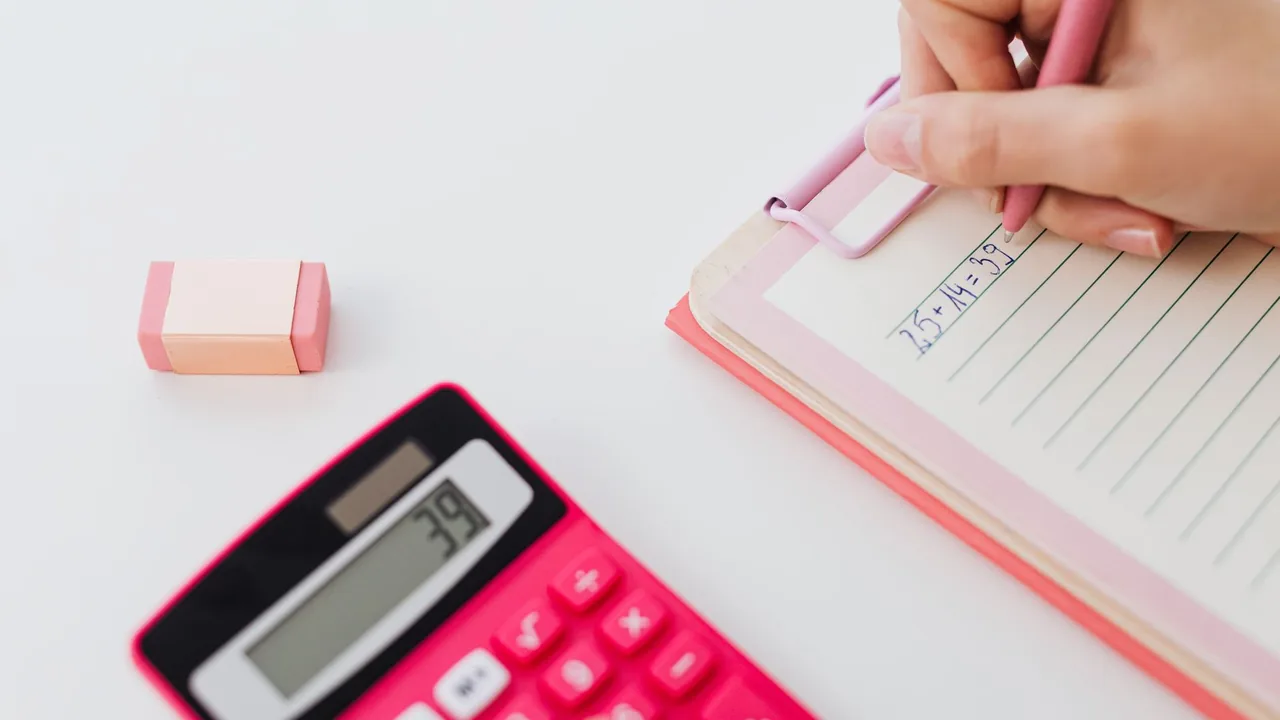 A calculator, pen and notebook on a desk.